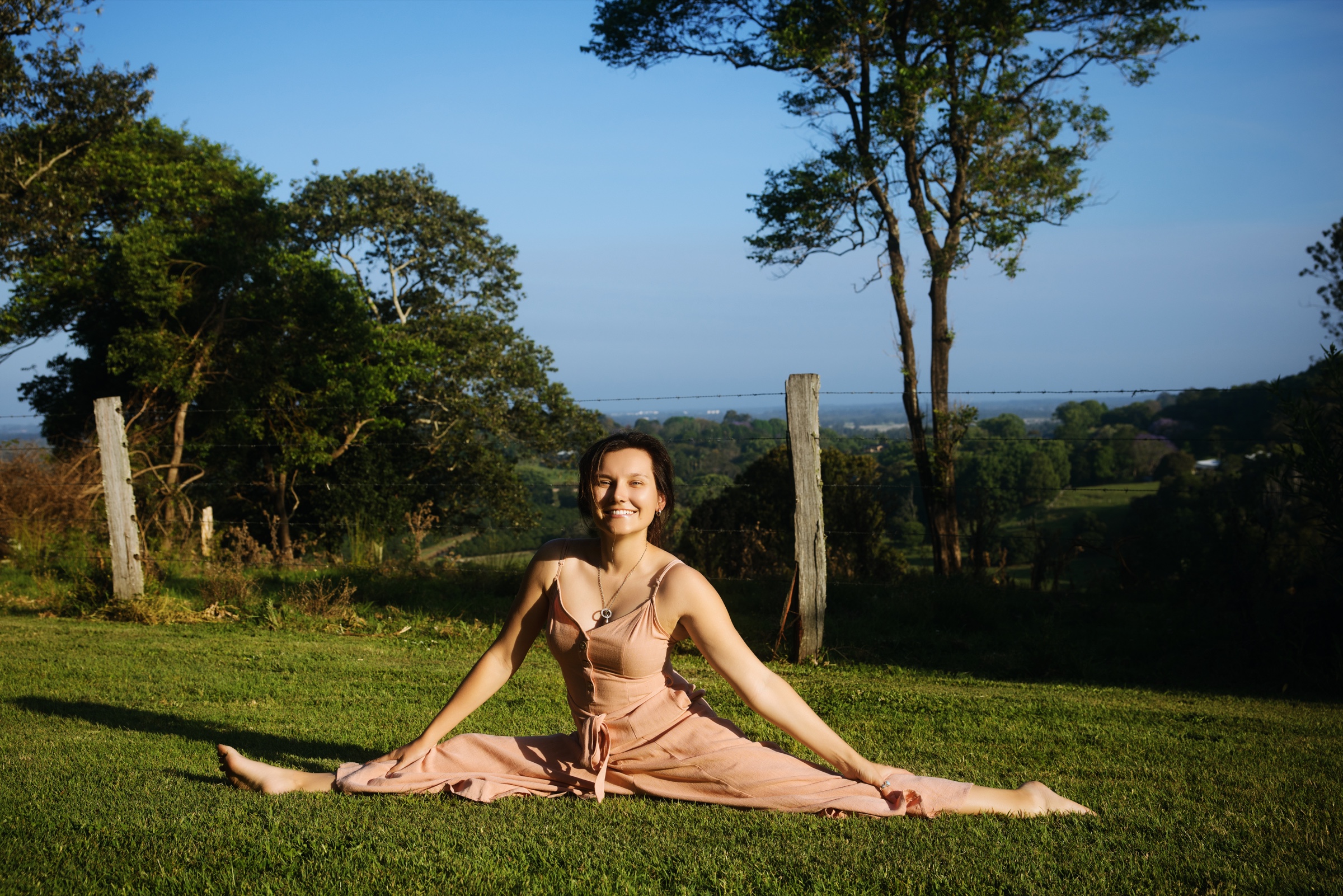 Natalie seated in a wide split on the lawn at Tides Byron Estate