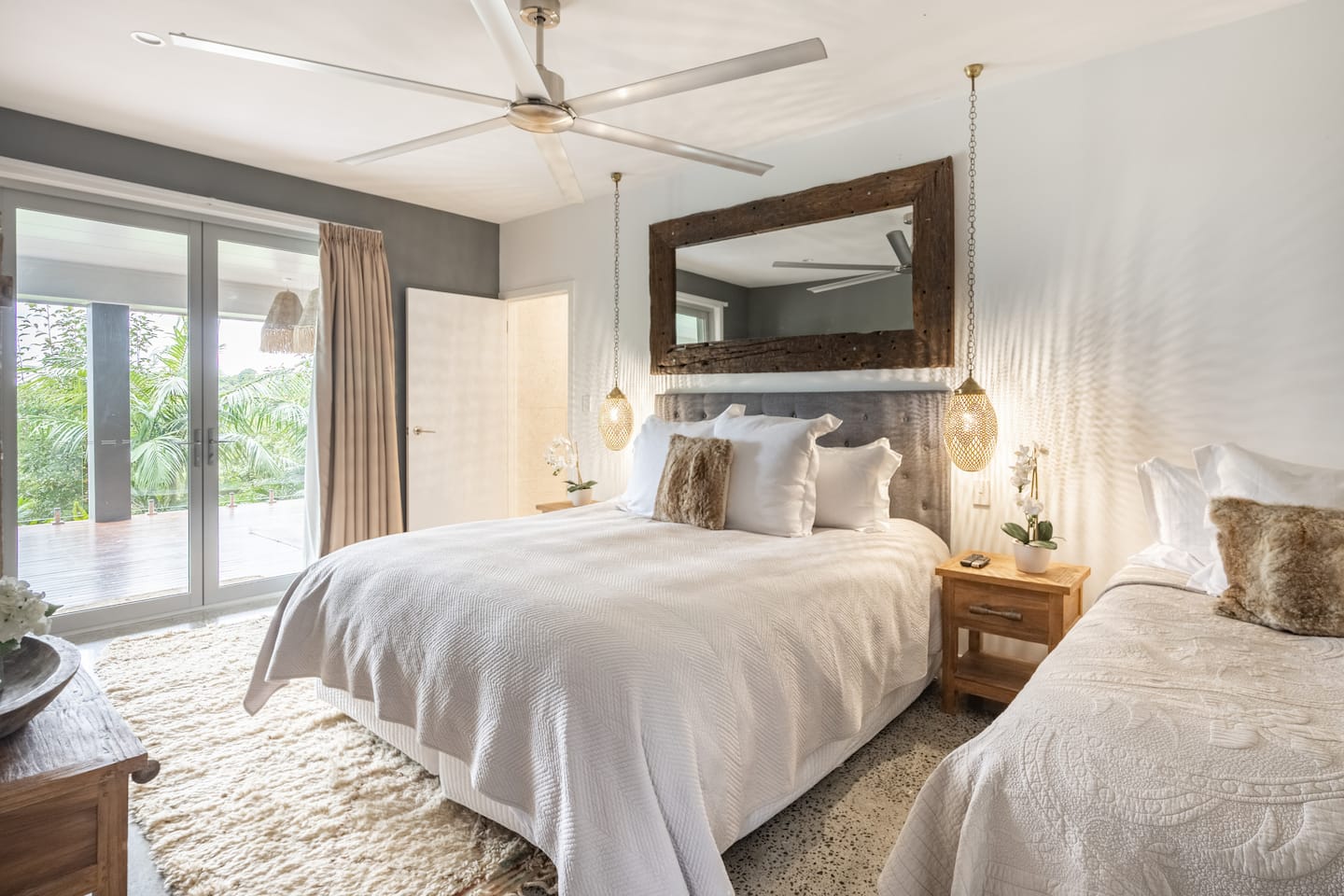 A bright Tides Villa bedroom with timber details and doors opening to the terrace